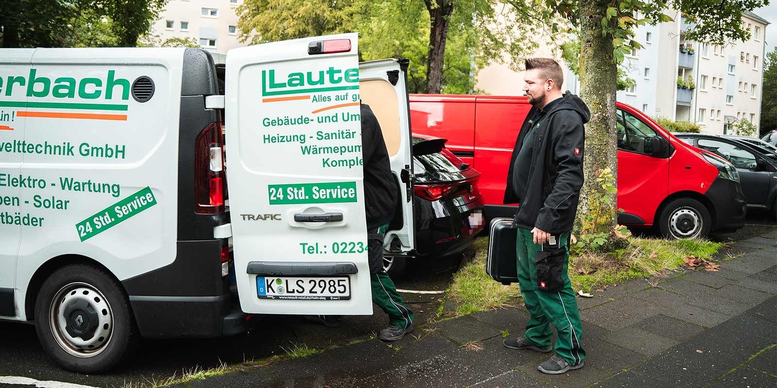 Ein Techniker steht neben einem Lieferwagen, der mit Dienstleistungen für Sanitär und Heizung beschriftet ist.